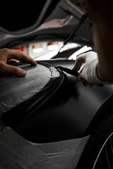 Vinyl film is carefully applied and trimmed with a blade for flawless vehicle wrapping results....
