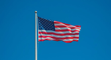 Fototapeta premium American Flag Waving Against Blue Sky