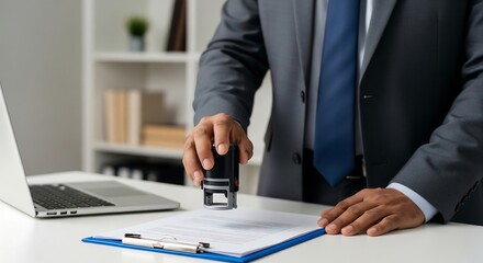 Business professional stamping a document. Man in a suit is holding a rubber stamp over a document on a clipboard in an office setting.