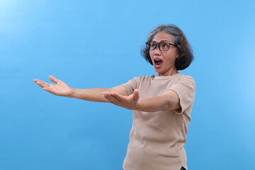 Asian elderly woman with gray hair, wearing glasses, standing looking up, facing sideways, gesture...