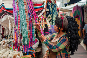 Tourist choosing colorful handcrafted souvenirs at otavalo market