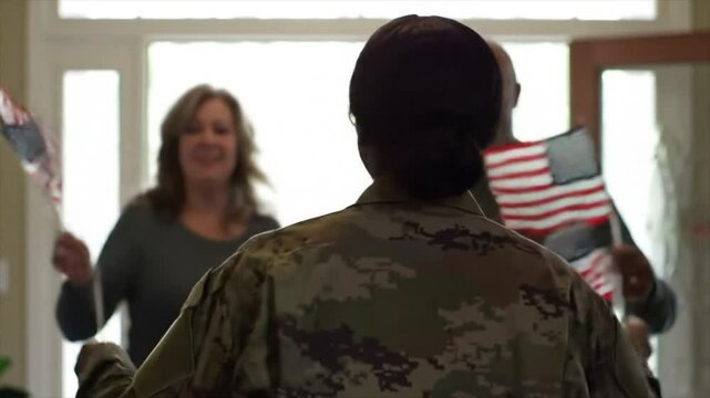 A soldier is greeted by joyful family members holding flags upon returning home. The emotional atmosphere captures the joy of reunion and gratitude for service