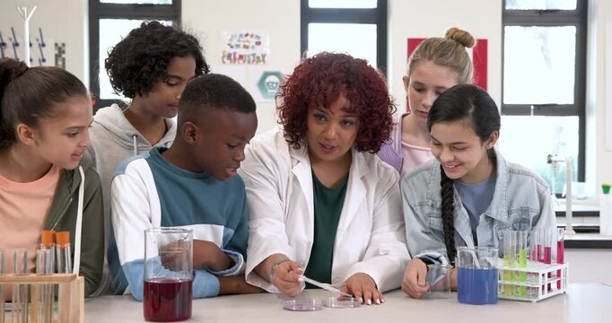 Female teacher guiding diverse multiracial students in science experiment with test tubes, at school