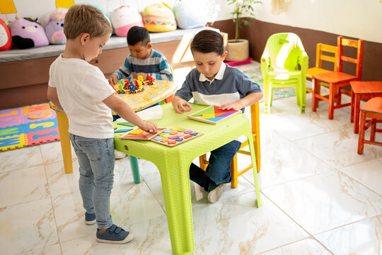 Group of young boys playing with educational toys and puzzles in a bright kindergarten classroom, Preschool kids are developing fine motor skills and cognitive abilities through learning activities.