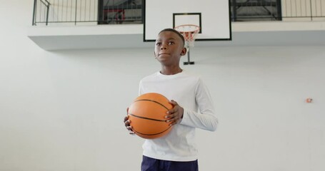 african american boy holding basketball in gym, looking determined and focused, copy space - Powered by Adobe