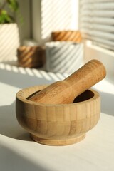 Wooden mortar and pestle on windowsill indoors, closeup