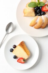 Tasty bundt cake with powdered sugar, berries and mint on white table, flat lay