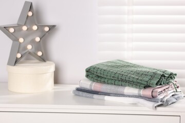 Wool scarves, box and star shaped lamp on white nightstand indoors