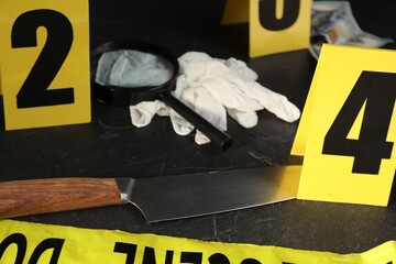 Forensic expert. Yellow crime scene tape, markers and evidences on black table, closeup