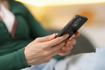 Woman using modern smartphone on sofa at home, closeup