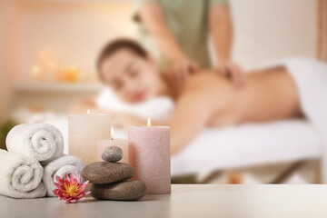 Spa therapy. Woman receiving massage on table and composition with stones, candles and towels in...