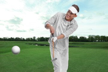 Golfer hitting ball with club on course