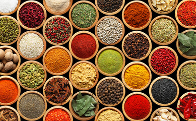 Set of different aromatic spices in bowls on black background, flat lay