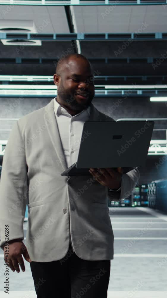Poster vertical video smiling server room engineer performing maintenance on server racks using software on