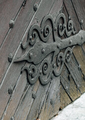 Ornate Wrought-Iron Hinge on Weathered Wooden Door
