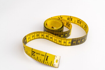 Oblique view of yellow - black measuring tape  on white background 