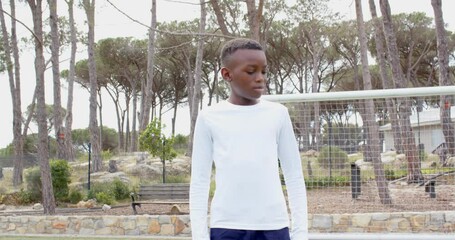 Focused african american boy standing on field near soccer goal, determined, copy space