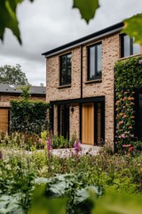 Fototapeta premium Modern brick house with large windows surrounded by lush garden, showcasing vibrant flowers and greenery during a cloudy day in a suburban area