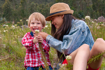 Big sister sharing wild flowers with smiling little brother in meadow