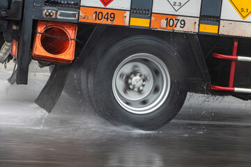Detail of the wheel of a truck driving on a wet road during rain.
