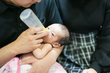 A two-week-old Japanese baby lies wrapped in a pink blanket, held close in the arms of loving...