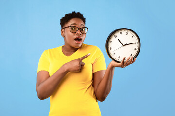 Deadline, Time Is Over. Oversized African Woman Showing Clock Posing Standing Over Blue Studio...