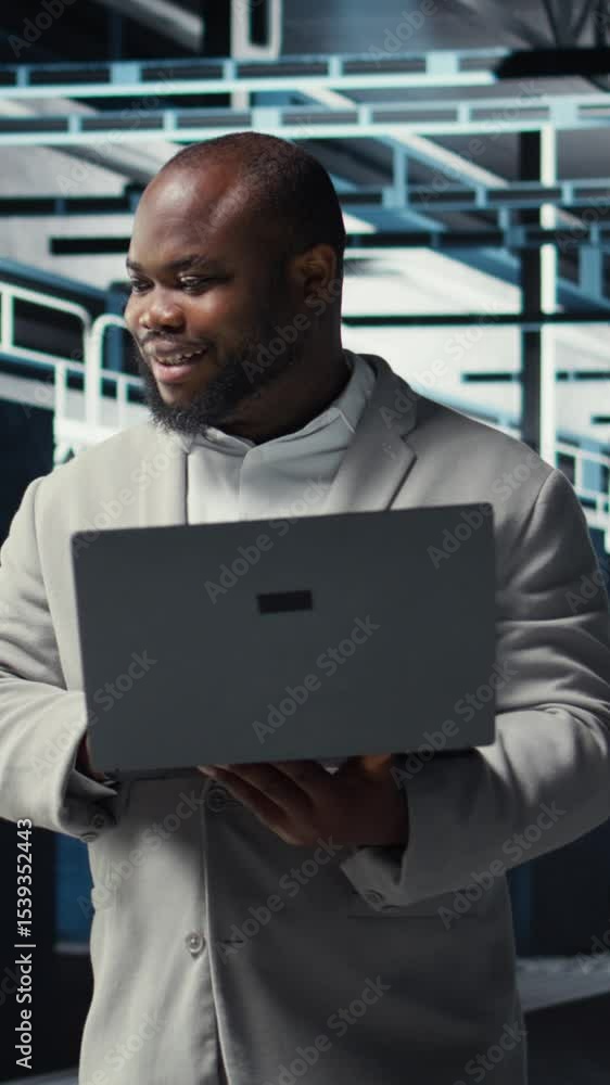 Poster vertical video smiling engineer in data center managing software updates for system stability using 