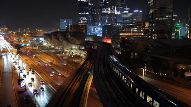 Drone aerial video following the Riyadh Metro into KAFD Metro Station at night, Saudi Arabia