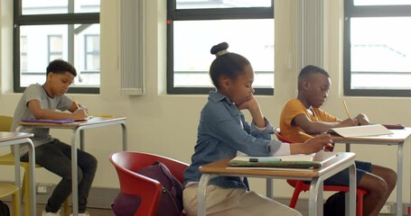 In classroom, multiracial students focused on writing assignments at desks, at school - Powered by Adobe