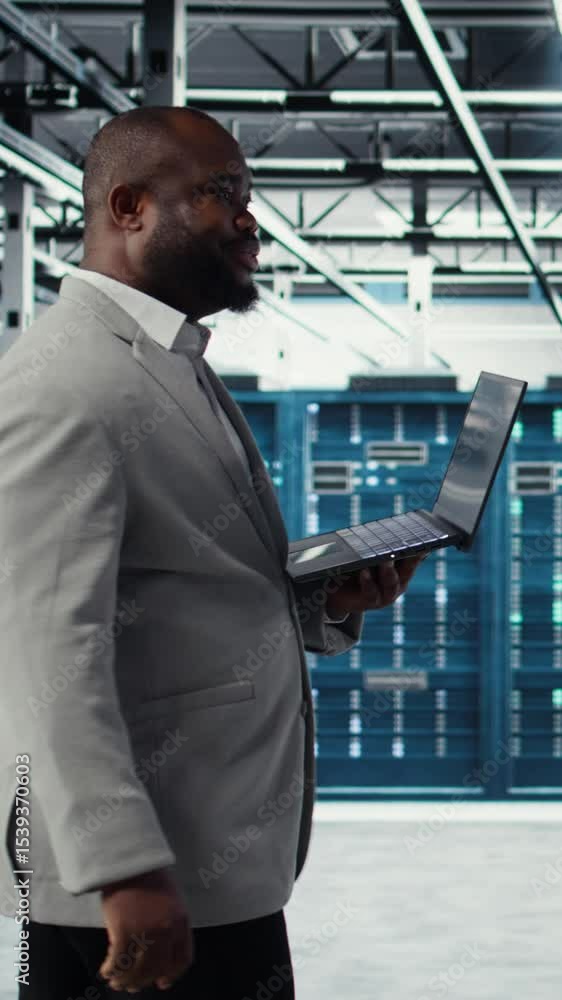 Poster vertical video smiling data center programmer using laptop to upgrade system stability. jolly africa