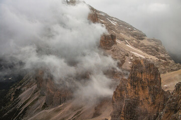 Aerial view of a rocky mountain peak partially obscured by low hanging clouds on a cloudy day outdoors