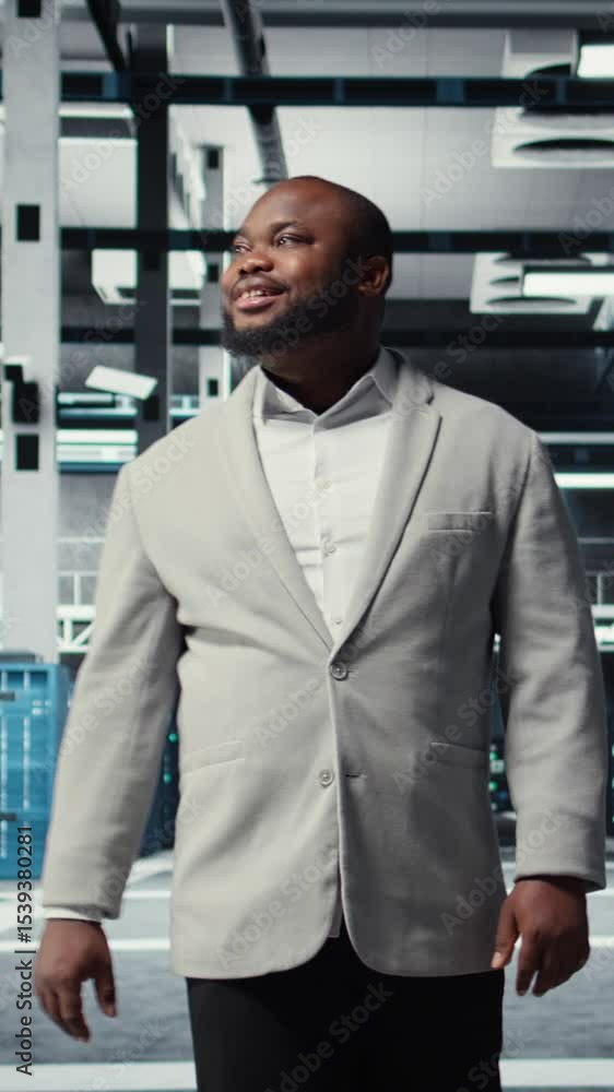 Poster vertical video smiling engineer walking in data center, checking hardware for system stability. happ