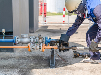The technician is connecting the gas delivery truck to the storage tank for refilling.