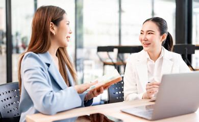 Fototapeta premium Smiling young business woman talking and discussing with her partner on coworking space.