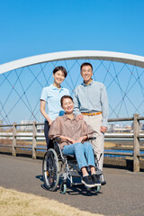 夫と車椅子に乗った妻と介護士　屋外　ポートレート　カメラ目線