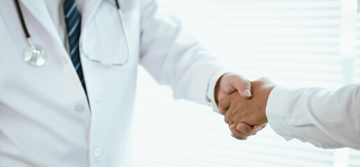 Two doctors in lab coats shaking hands, symbolizing trust, teamwork, and professional collaboration...