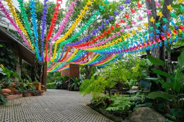 Colorful paper birds hang in vibrant outdoor garden, creating festive and lively atmosphere