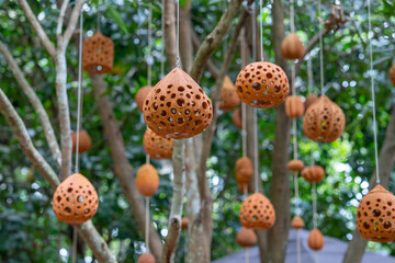 Hanging clay lanterns with intricate patterns sway gently among lush green trees