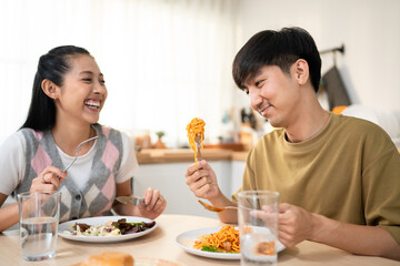 Asian young couple husband and wife eat food on dinner table in house.