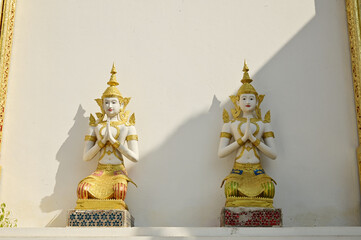 A Thai art statue of an angel in a seated position with hands clasped together, decorated on the side wall of the chapel in the temple area at Wat Den Sali Si Mueang Kaen temple. At Cheng Mai,Thailand