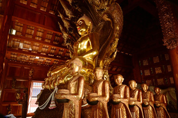 Golden sitting Buddha statue and there is a serpent covering the back in Buddhist Thai Church at Wat Den Sali Si Mueang Kaen temple. Located at Chiang Mai city in Thailand.