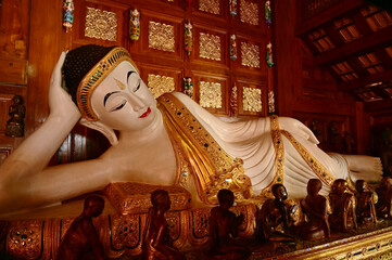 The Reclining white statue Buddha is enshrined in a teakwood chapel at Wat Den Sali Si Mueang Kaen temple or Wat Ban Den. Located at Cheng Mai Province in Thailand.