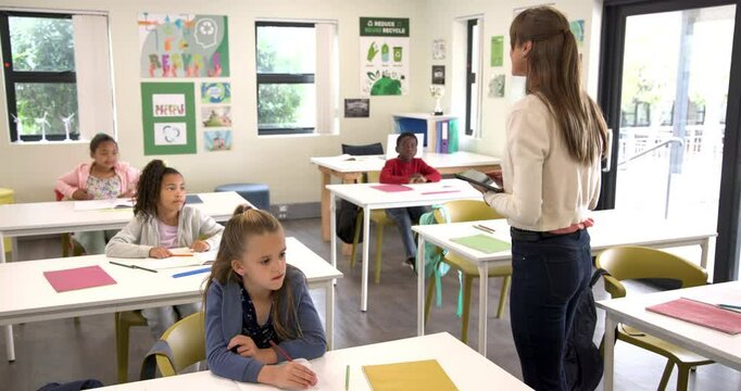 Students eagerly raising hands in classroom while teacher holds tablet - Powered by Adobe