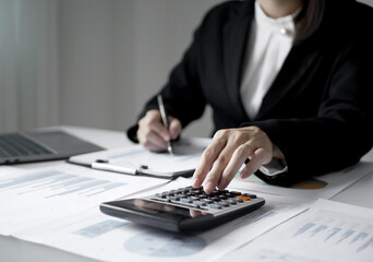 Young Asian business woman sitting at the table holding a pen, recording investments and planning the process of growing a successful business