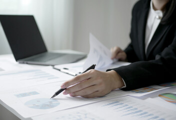 Young Asian business woman sitting at the table holding a pen, recording investments and planning the process of growing a successful business