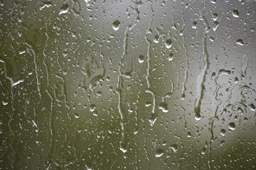 Raindrops on a window create a beautiful, natural pattern with blurred, abstract textures.