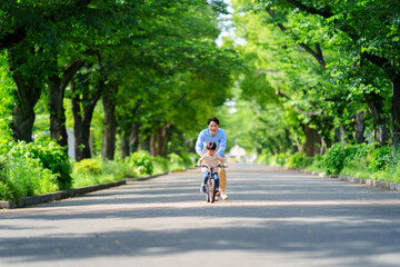 Obraz premium 両親と自転車の練習をする5歳の少年