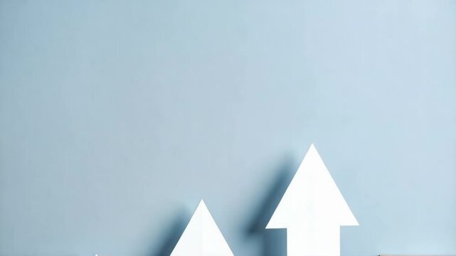 Paper airplane on wood blocks with increasing arrow signs, concept for progress, ambition, and business goals on a gray background