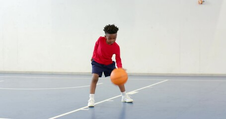 Practicing basketball dribbling, african american boy focused on indoor court, copy space - Powered by Adobe