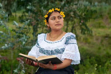 Indigenous woman wearing traditional clothes reading a book in nature